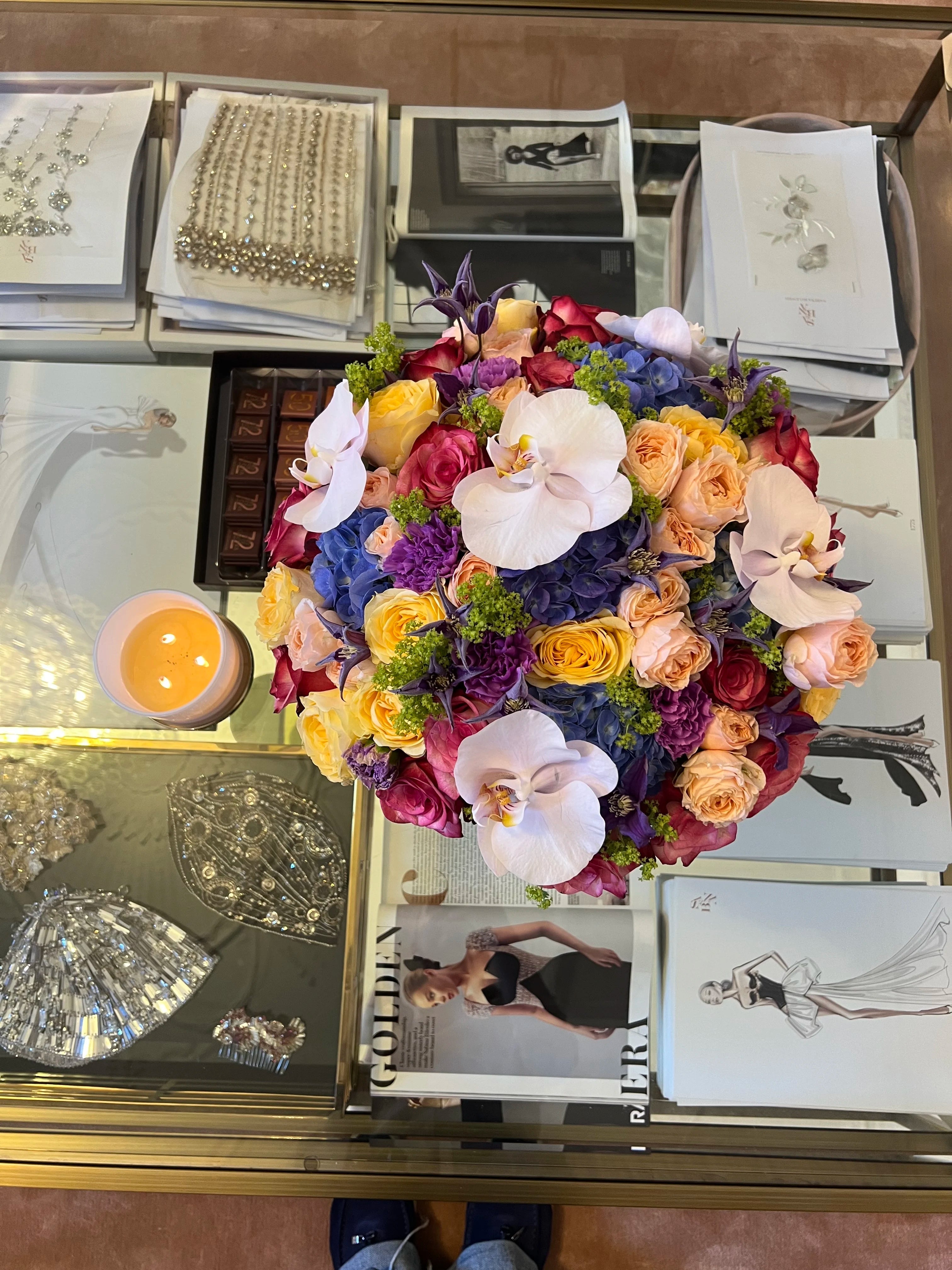 Colorful bouquet of flowers on a surface with books and jewelry.