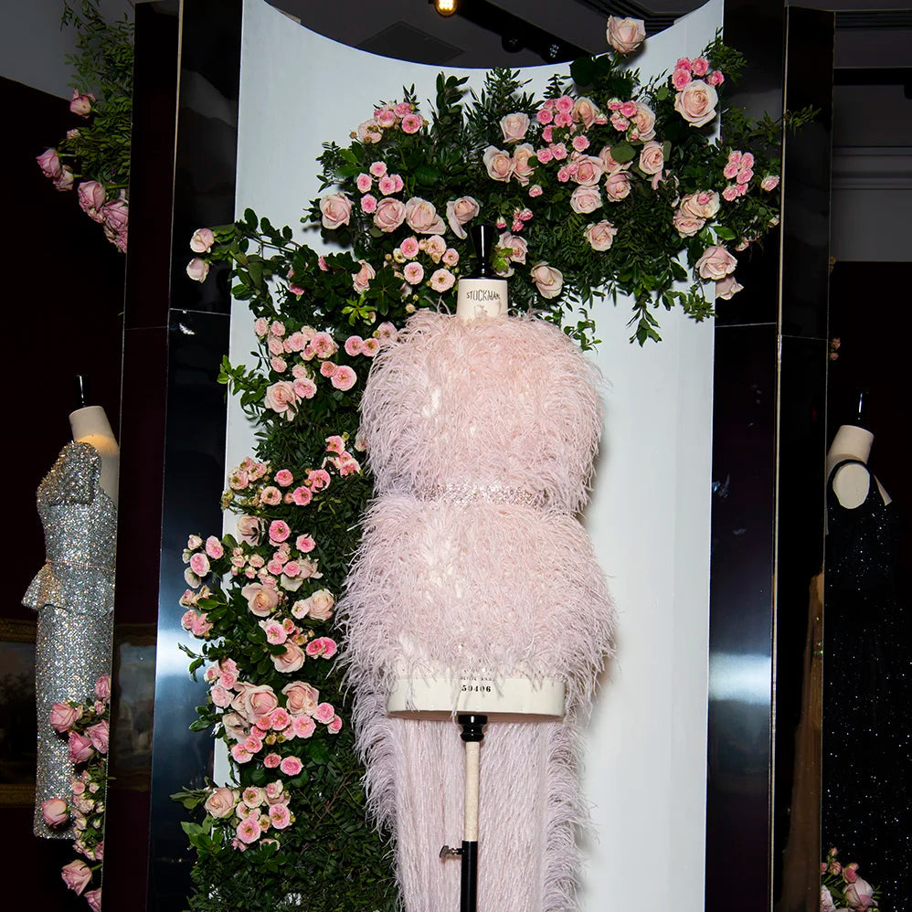 Feathered dress on a mannequin with floral decorations in a store setting