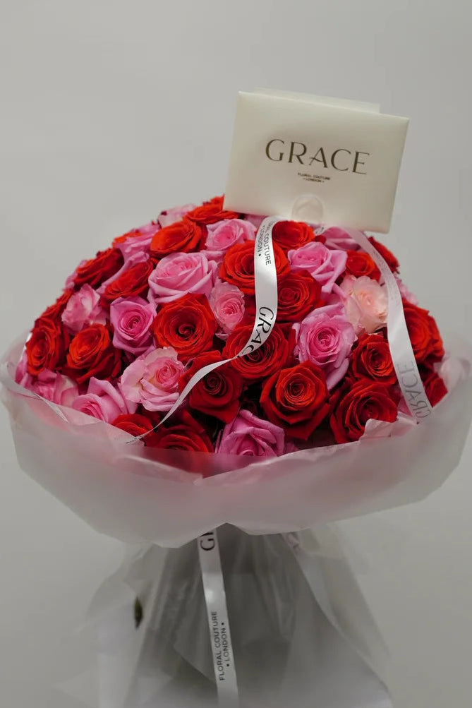 Bouquet of red and pink roses with a 'GRACE' tag on a white background